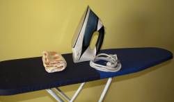 En la imagen: trapo de cocina, y plancha sobre una tabla de planchar. En la imagen: trapo de cocina, y plancha sobre una tabla de planchar.